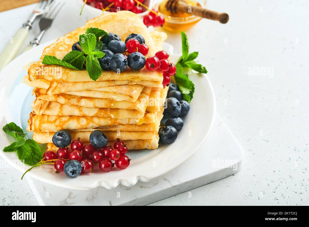 Pfannkuchen. Stapel von Crepes oder dünnen Pfannkuchen mit Beeren, Heidelbeeren, roten Johannisbeeren, Himbeeren und Honig zum Frühstück. Hausgemachtes Frühstück. Kopieren Sie den SPAC Stockfoto