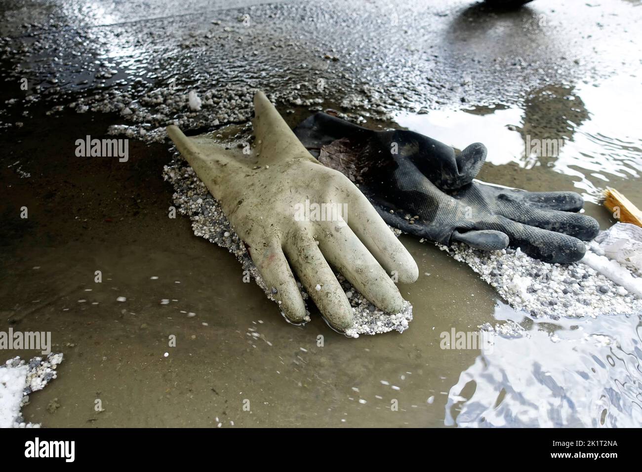 Handschuhe eines Bauarbeiters in einer Pfütze Stockfoto