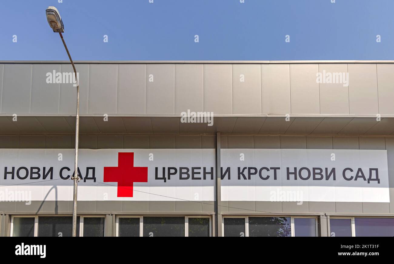 Novi Sad, Serbien - 19. August 2022: Langes Bannerschild Rotes Kreuz Novi Sad Kyrillische Schrift im Bürogebäude. Stockfoto