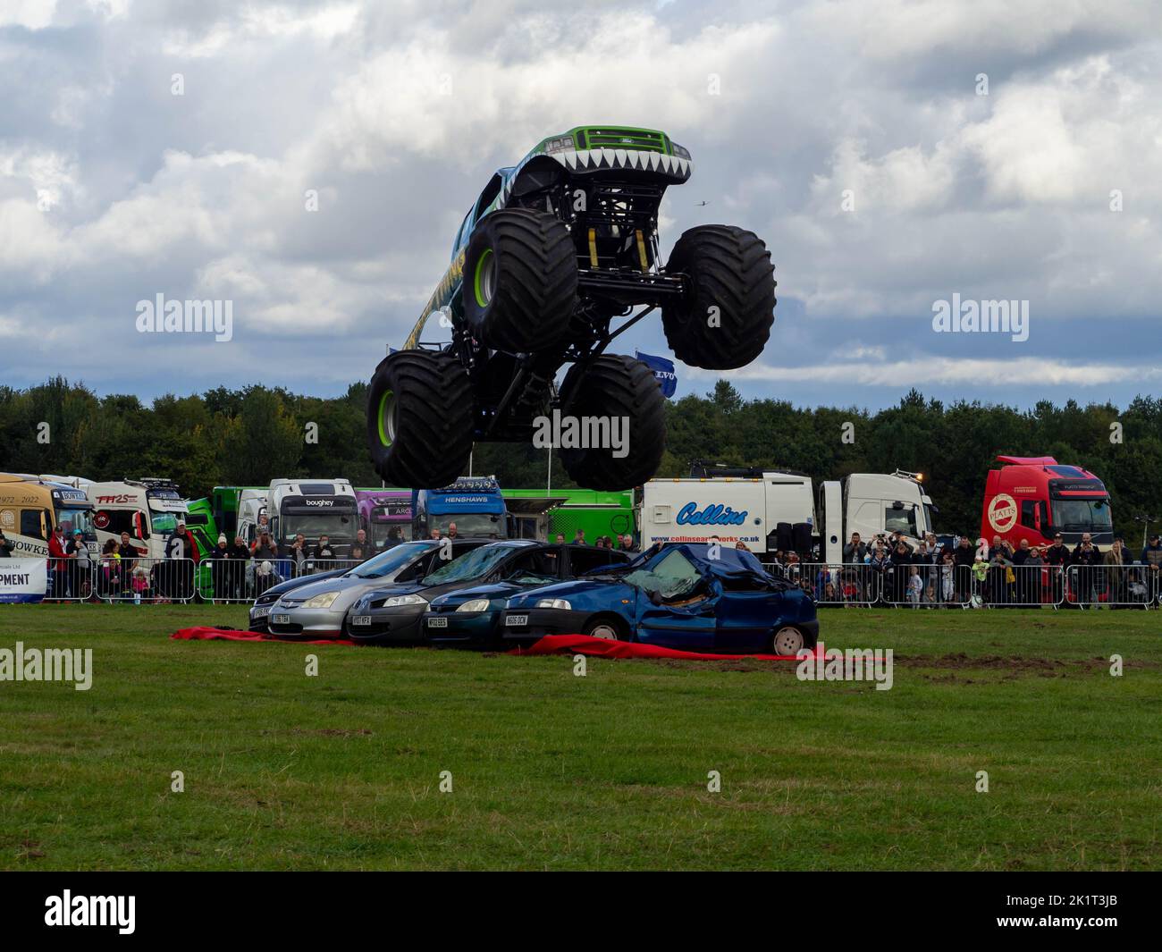 Sumpf-Ding Monster Truck demonstriert seine Fähigkeiten beim Springen über Autos, actiongeladene Fotografie Stockfoto