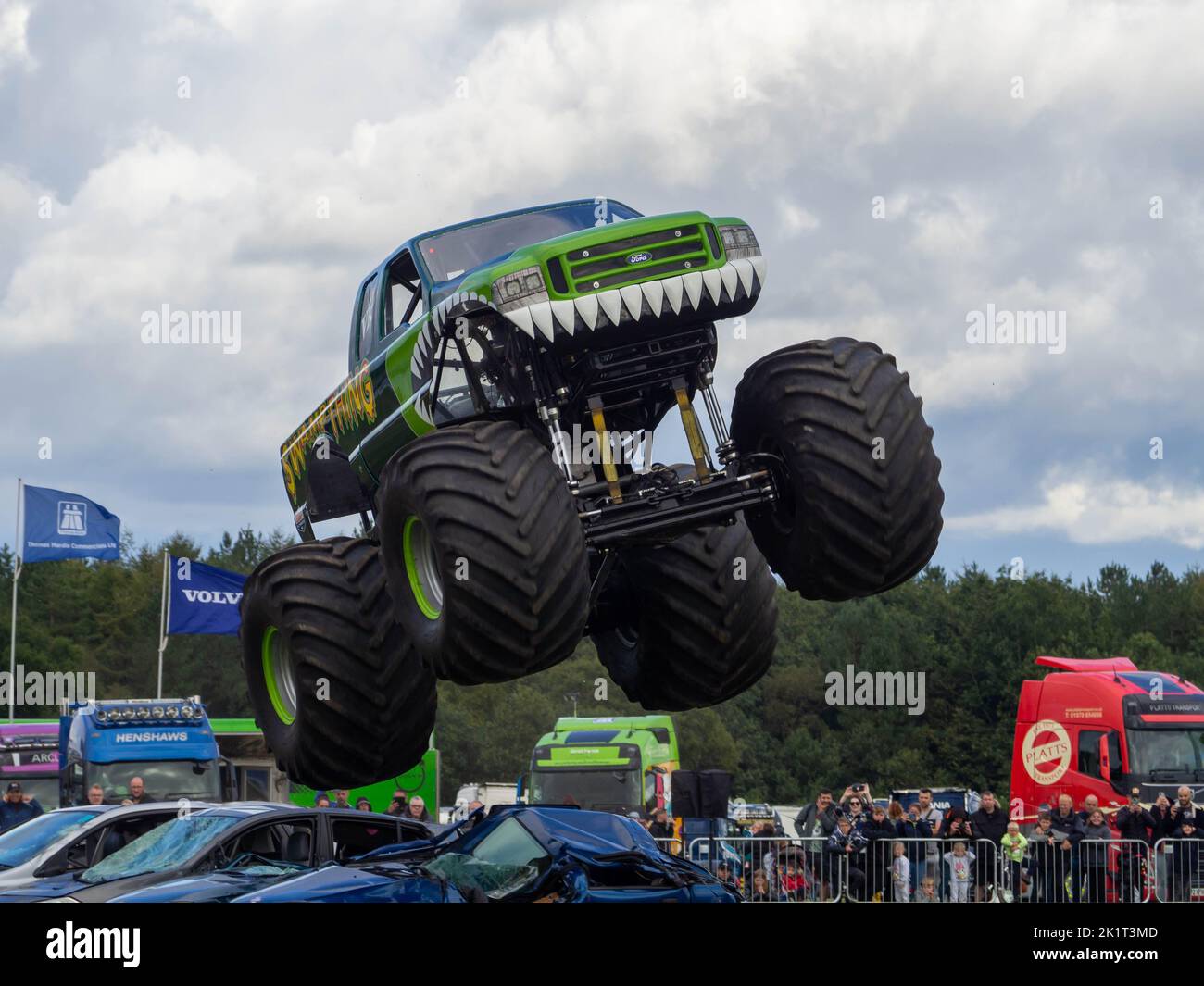 Sumpf-Ding Monster-Truck, der über Autos springt, hat mitten im Sprung actiongeladene Fotos aufgenommen Stockfoto