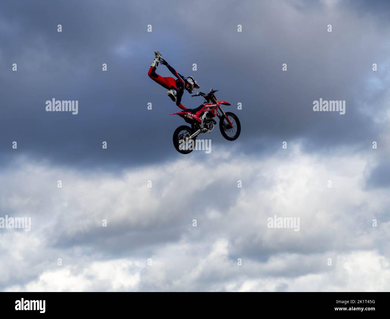 Brach FMX Stunt Rider eine hohe Stunt-Pose auf dem Rücken eines Motorrads, oben in den Wolken an einem kühlen Herbsttag auf dem Truckfest NW. Stockfoto