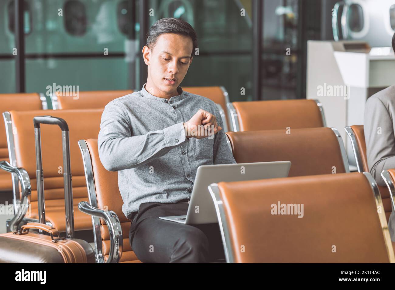 Ein Geschäftsmann, der am Flughafen langweilt und wegen der Verspätung des Fluges spät auf die Armbanduhr wartete und sich Sorgen machte Stockfoto