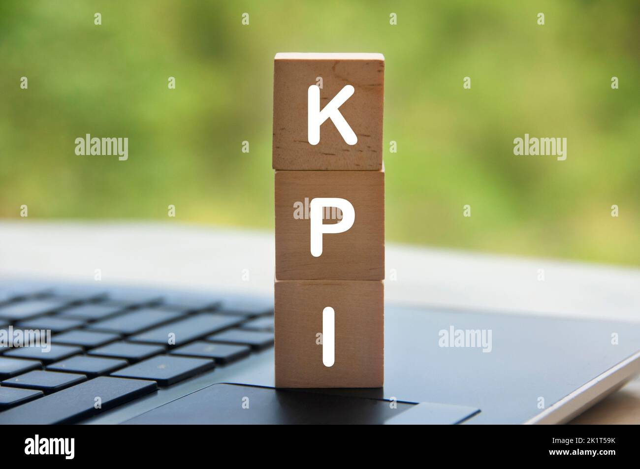 KPI-Text auf Holzblöcken mit Laptop und unscharfem Naturhintergrund. Geschäfts- und Key Performance Indicator Konzept. Stockfoto
