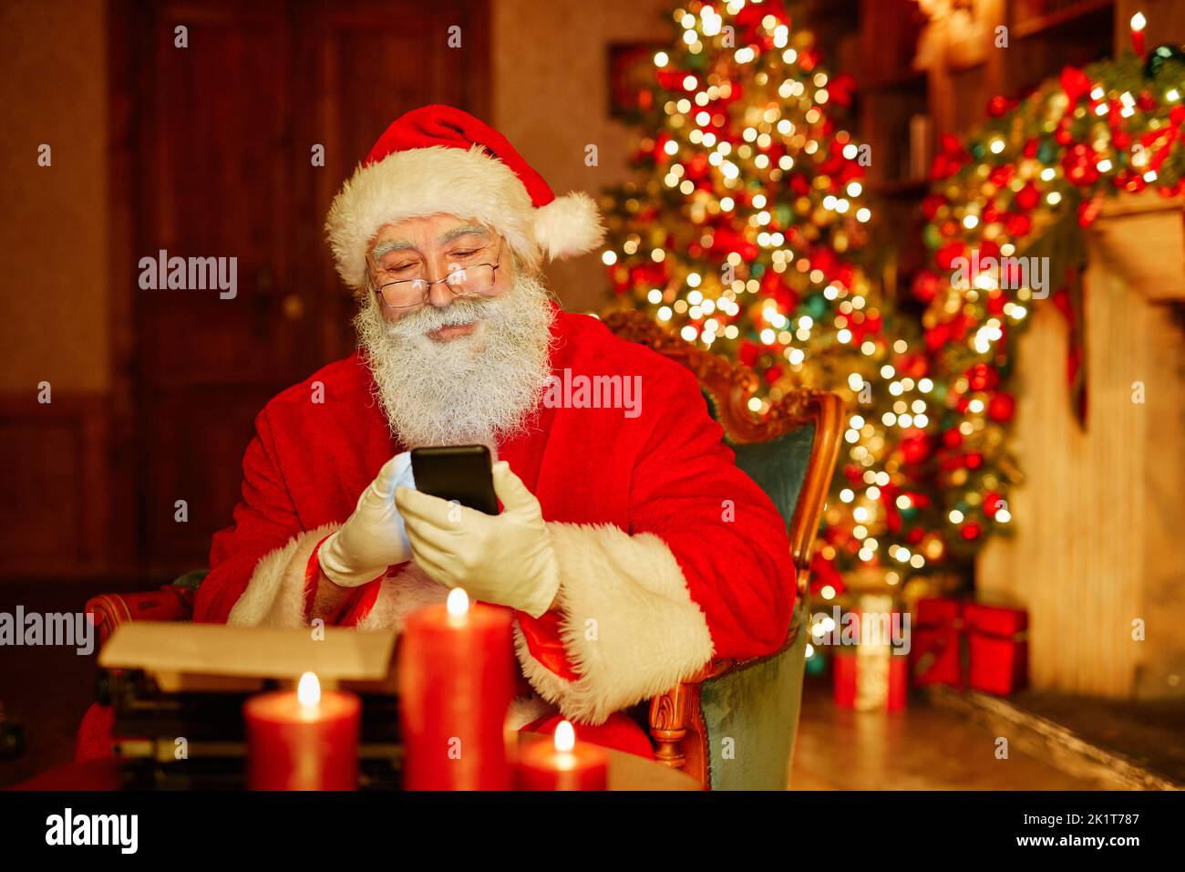 Porträt des traditionellen Weihnachtsmanns mit Smartphone in festlichen Raum mit Weihnachtsschmuck, kopieren Raum Stockfoto