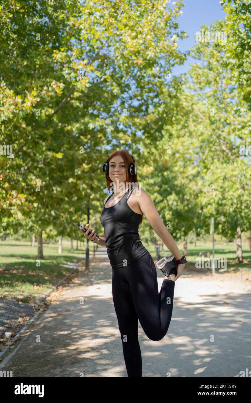 Porträt einer fitfen und sportlichen jungen Frau, die im öffentlichen Park Stretching macht. Stock-Fotografie Stockfoto