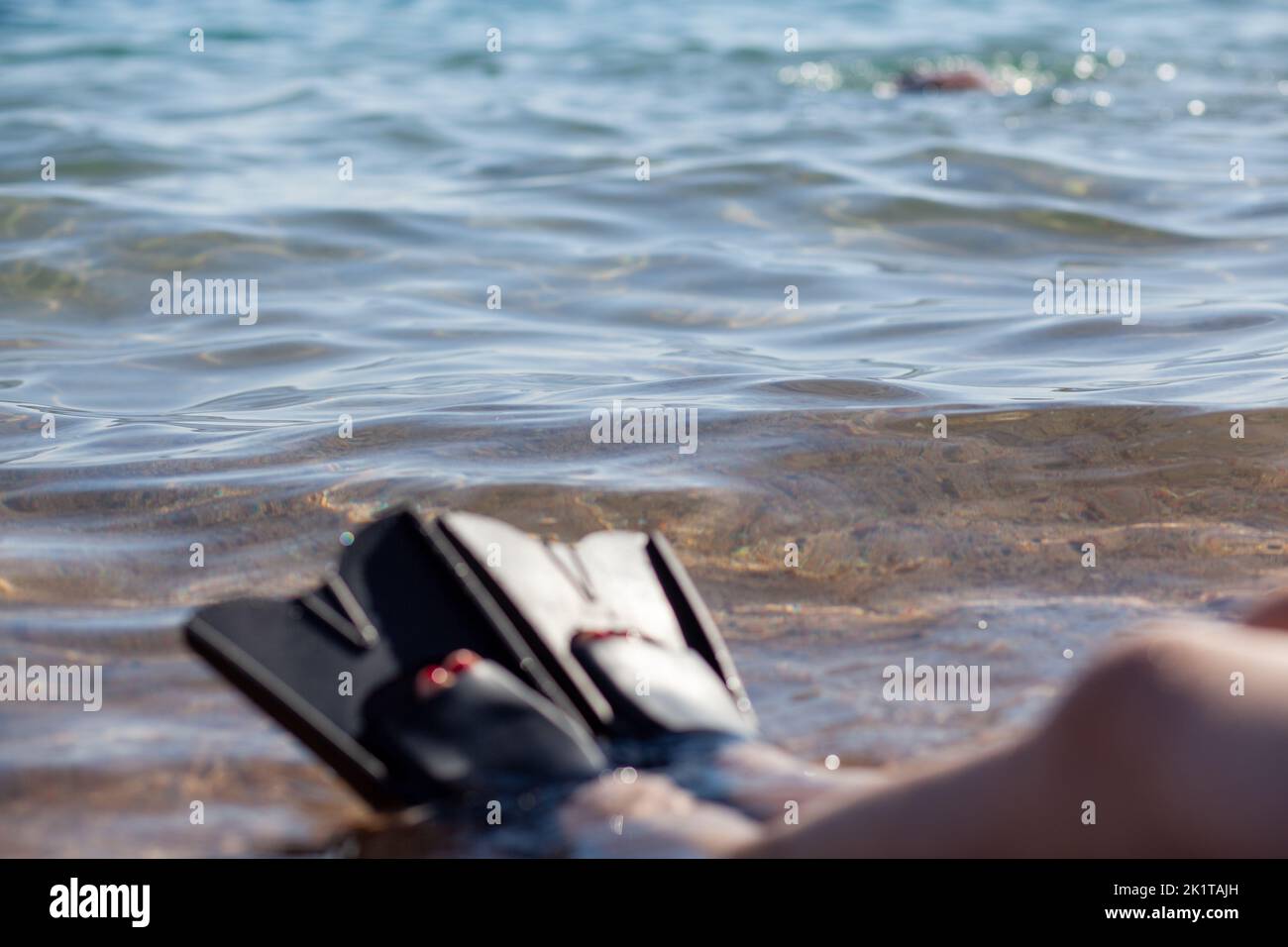 Eine Frau in schwarzen Flossen spritzt in der Nähe des Ufers. Lamellen ragen heraus Stockfoto