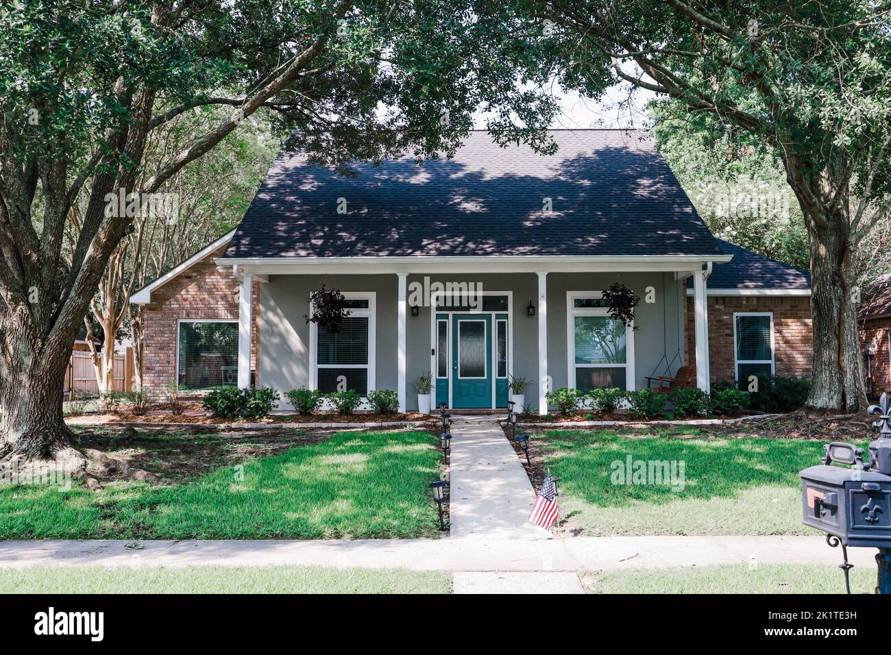 Eine Vorderansicht eines akadischen renovierten Hauses mit Säulen, Gehwegen und einer farbenfrohen Eingangstür, die kürzlich mit dem sich verändernden Immobilienmarkt gekauft wurde Stockfoto