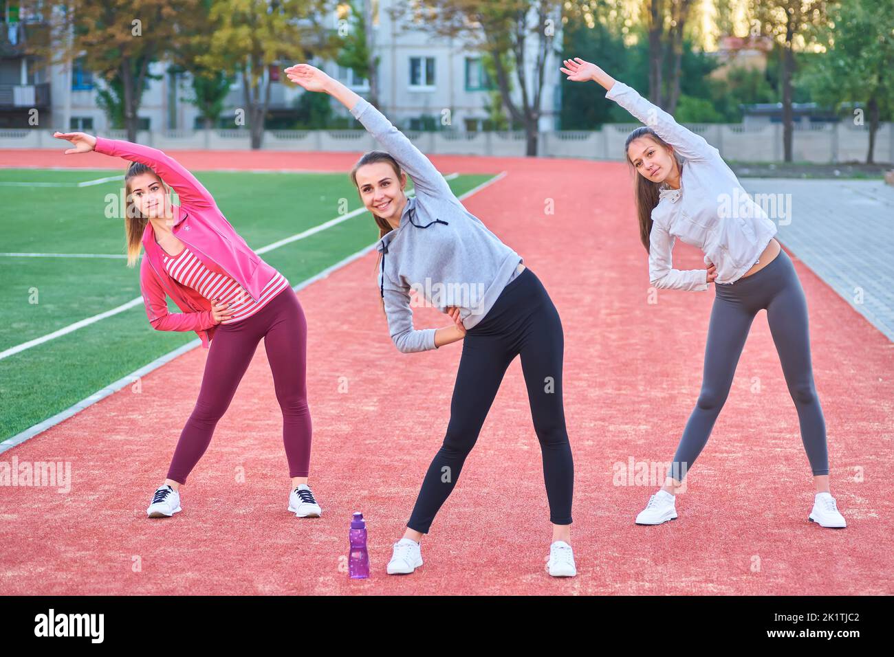 Positive Frauen Sport Übungen.. Die Gruppe der drei schöne junge Frauen, die Sport im sonnigen Tag im Park. Stockfoto