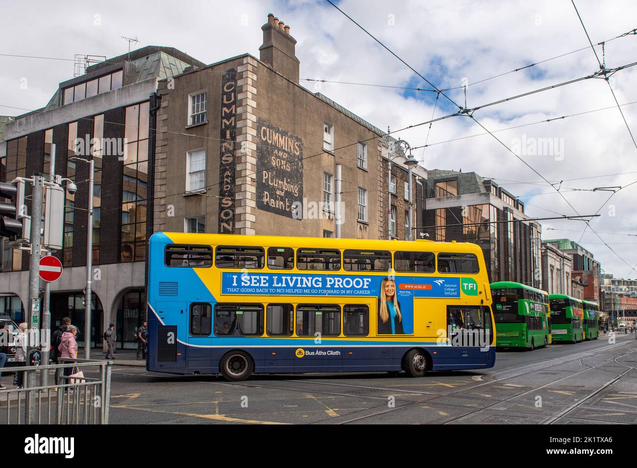 Dublin Bus fährt unter LUAS Tram-Oberleitungen in Dublin, Irland. Stockfoto