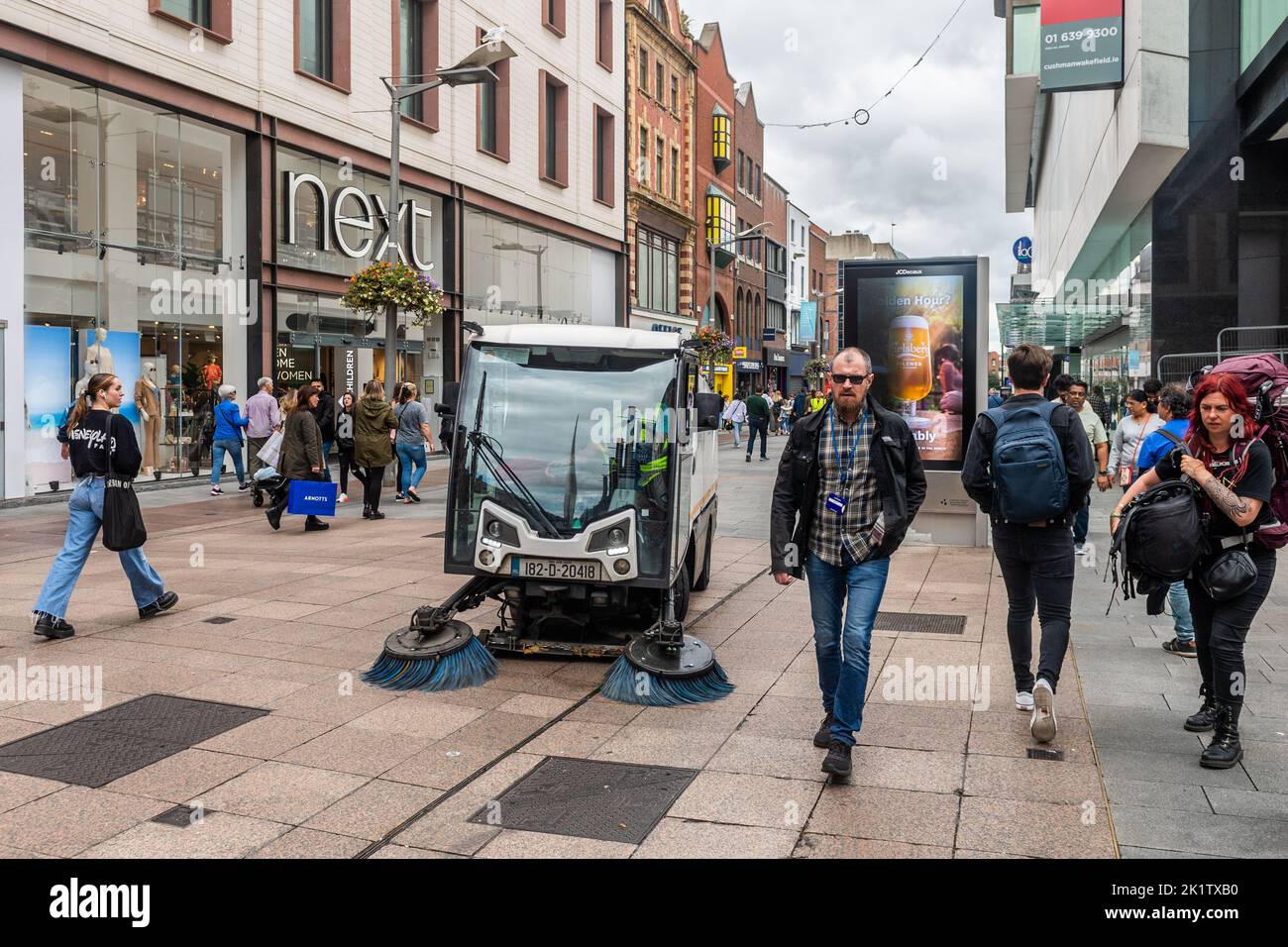 Straßenreiniger und Fußgänger auf der Henry Street, Stadtzentrum, Dublin. Stockfoto