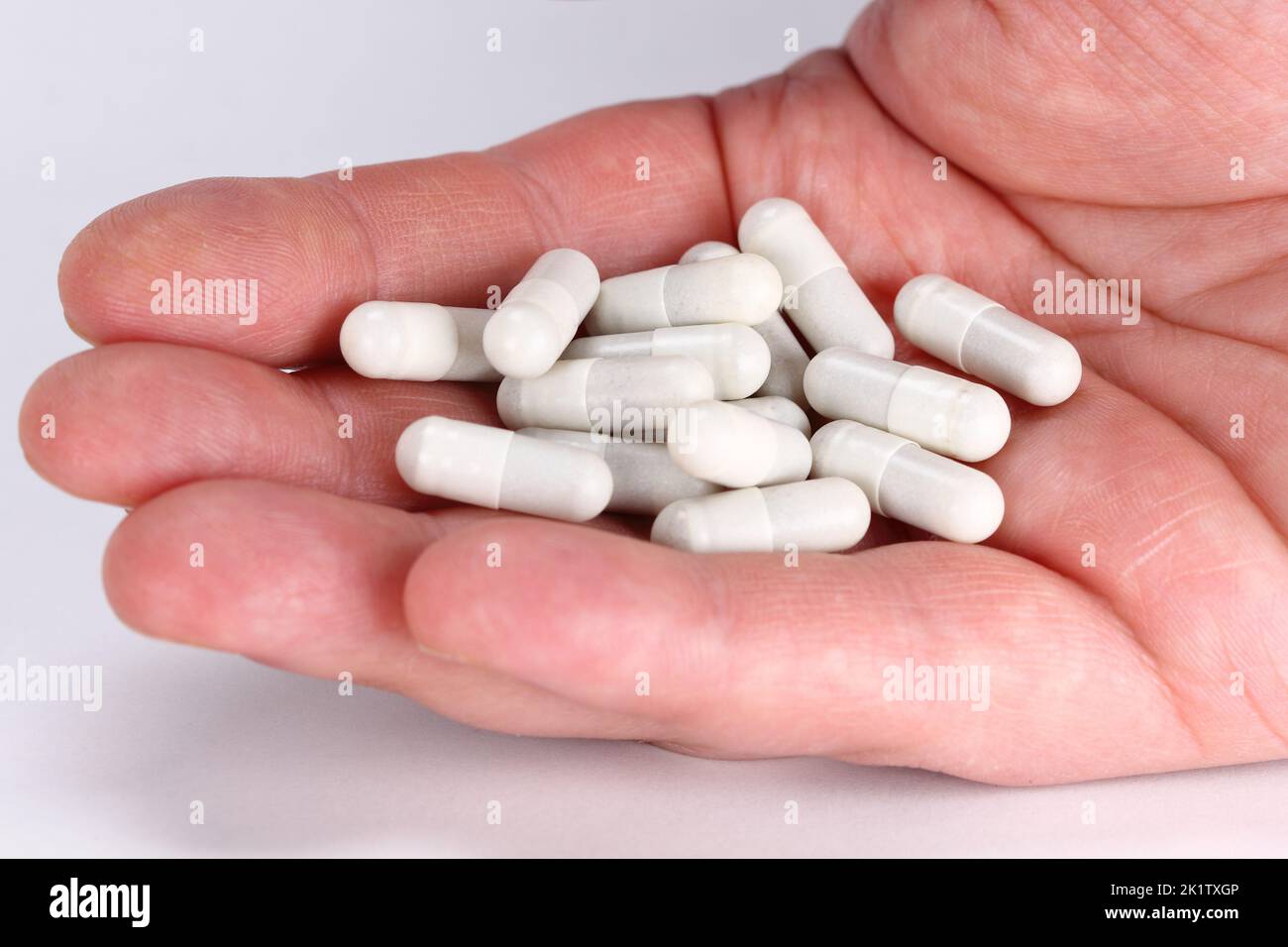 Mann Hand voll von weißen Tabletten, Pillen der Medizin auf weißem Hintergrund Stockfoto