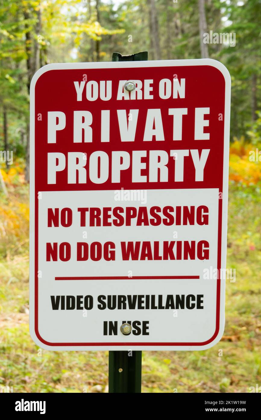 Ein rot-weißes Schild für Privateigentum, das vor dem Betreten, dem Gehen von Hunden und der Videoüberwachung warnt, ist in Gebrauch. Stockfoto