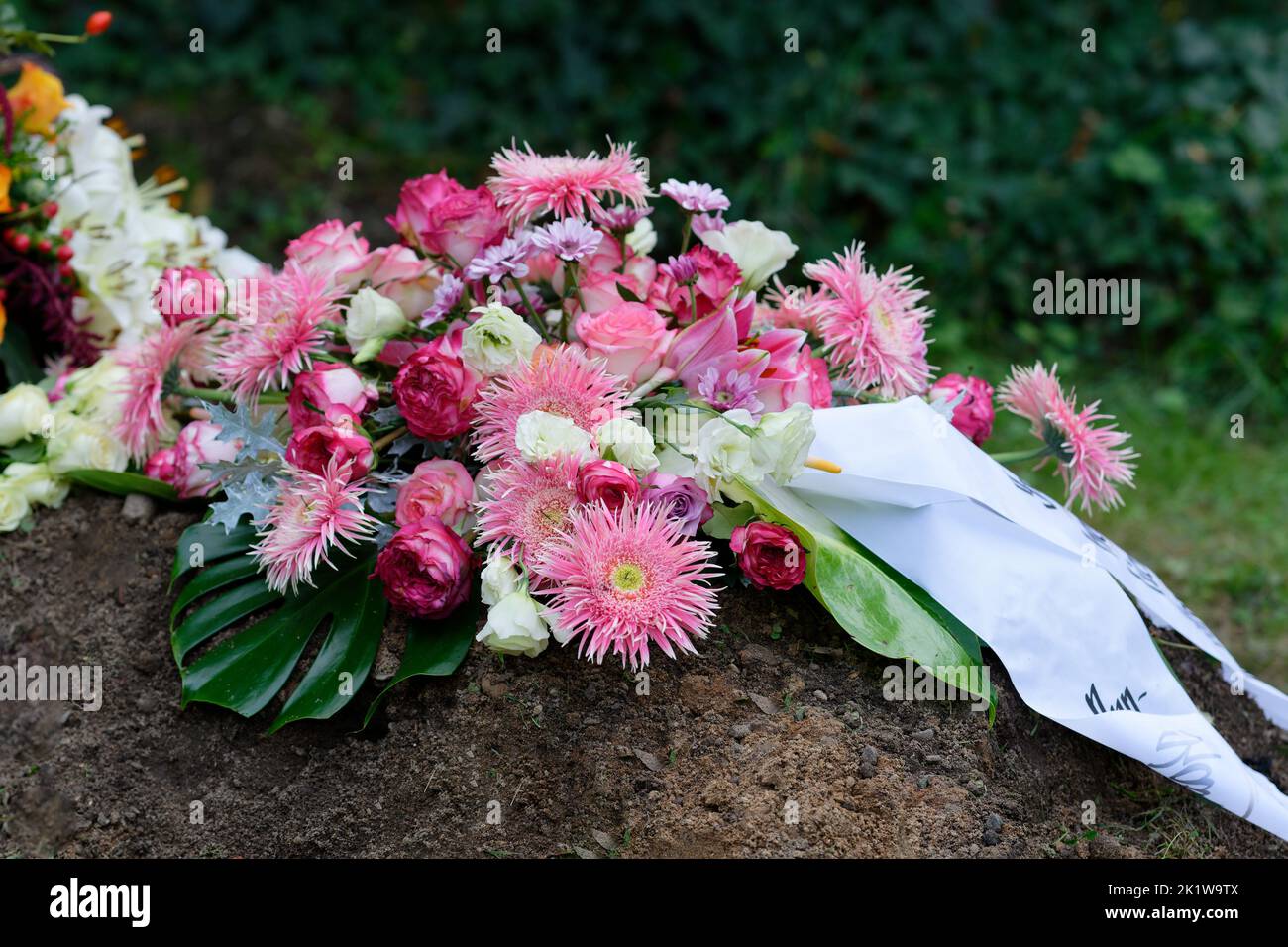 Farbenfrohe Blumenbesetzung auf einem Grab nach der Beerdigung Stockfoto