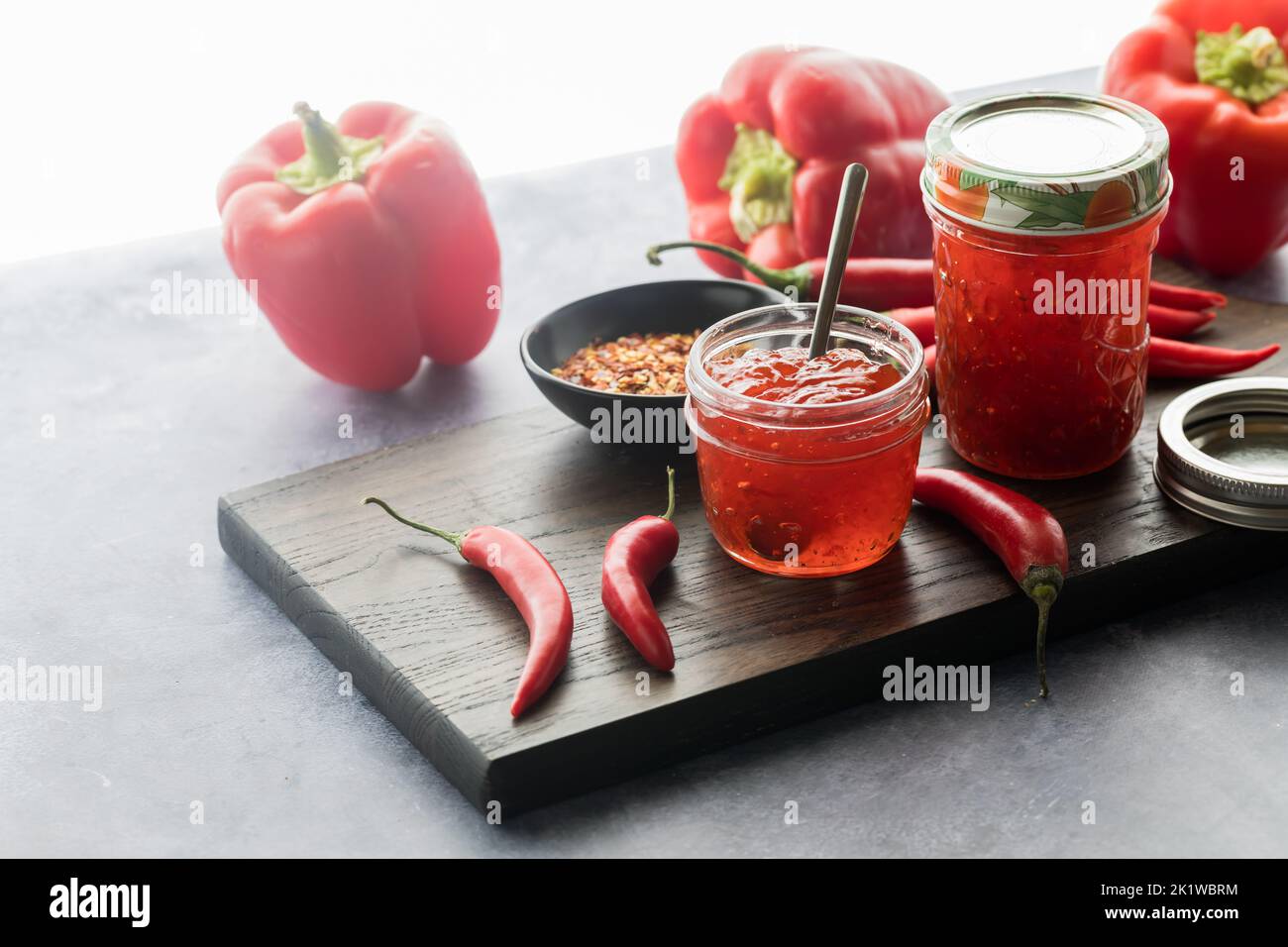 Gläser mit köstlichem Paprika-Gelee vor einem hellen, sonnigen Fenster. Stockfoto