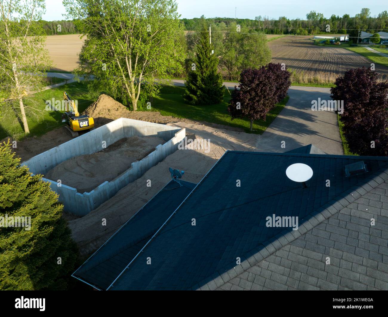 Ein Luftblick über ein Haus, das im Bau ist, mit einer SpaceX Starlink Satelliten-Internetschüssel auf dem Dach, die man spät am Tag sieht. Stockfoto