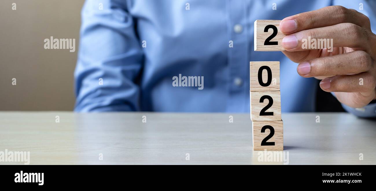 Business man Hand hält Holzwürfelblöcke mit 2022 Text auf dem Tischhintergrund. Lösung, Strategie, Lösung, Ziel, Geschäft, Neues Jahr Neu Sie und Stockfoto