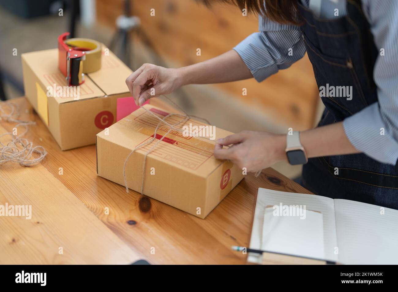 Junge Kleinunternehmerin verpackt Lieferungen in modernen Büro- und Lagerräumen Stockfoto