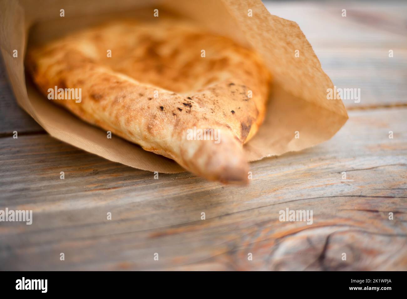 Eine handgebackene Tortilla liegt in einer Papiertüte auf einem Holztisch. Kraft. Nationales Brot. Umweltfreundliche Verpackung. Bio-Lebensmittel. Stockfoto
