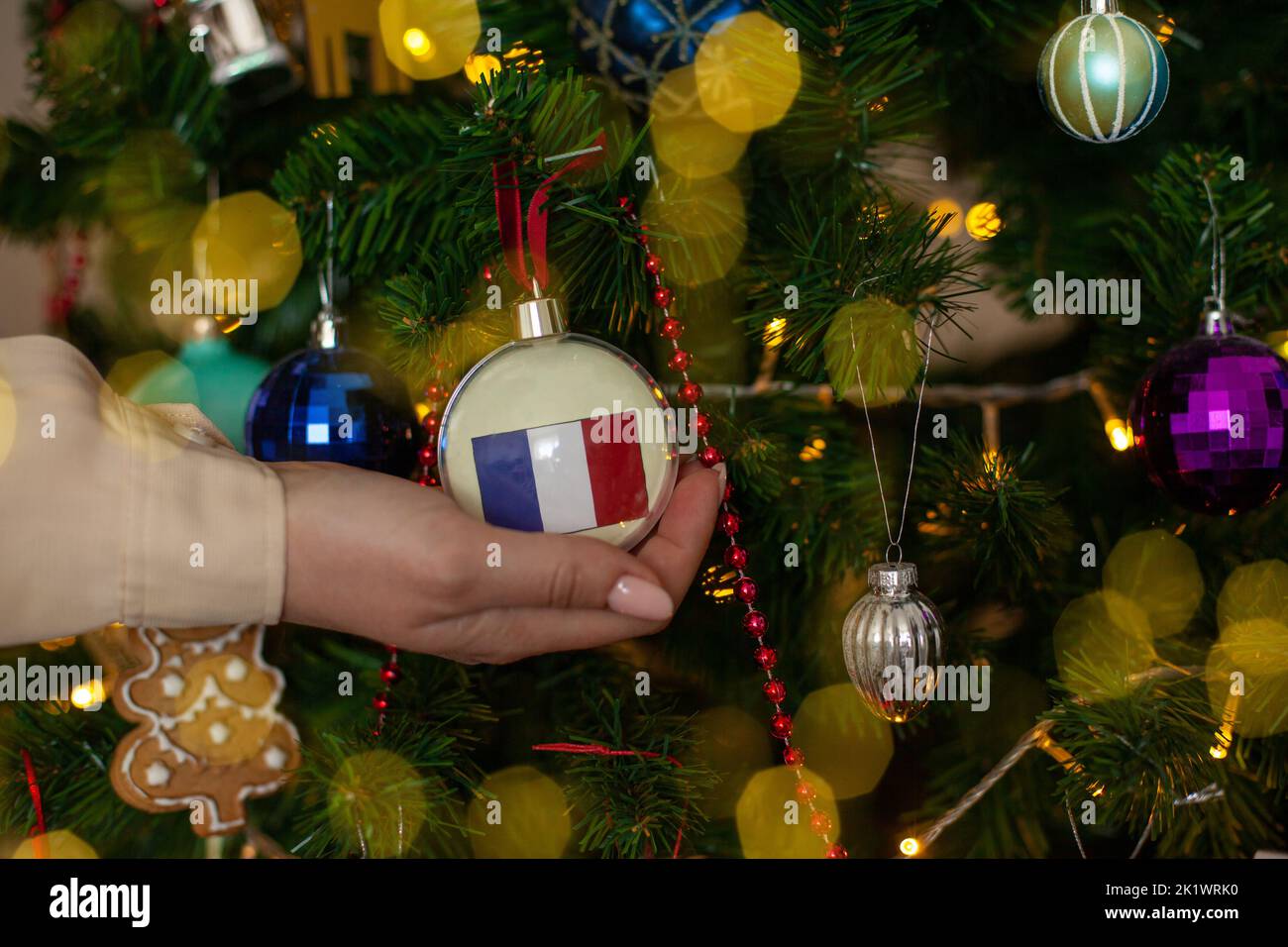 Nahaufnahme der Mädchen Hand hält einen Weihnachtsball für eine Tanne mit der Flagge von Frankreich. Neues Jahr in Frankreich. Weihnachtsfeiertag Grußkarte mit Kopie Stockfoto