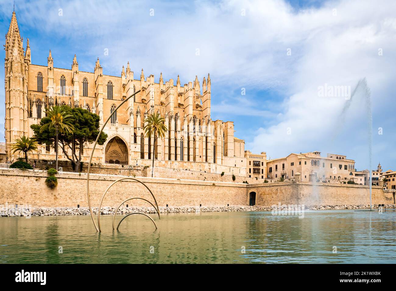 Seitlicher Blick auf die gotische Architektur der Kathedrale La Seu von St. Mary hinter der Stadtmauer von Palma de Mallorca und dem Teich des öffentlichen Parc de la mar. Stockfoto