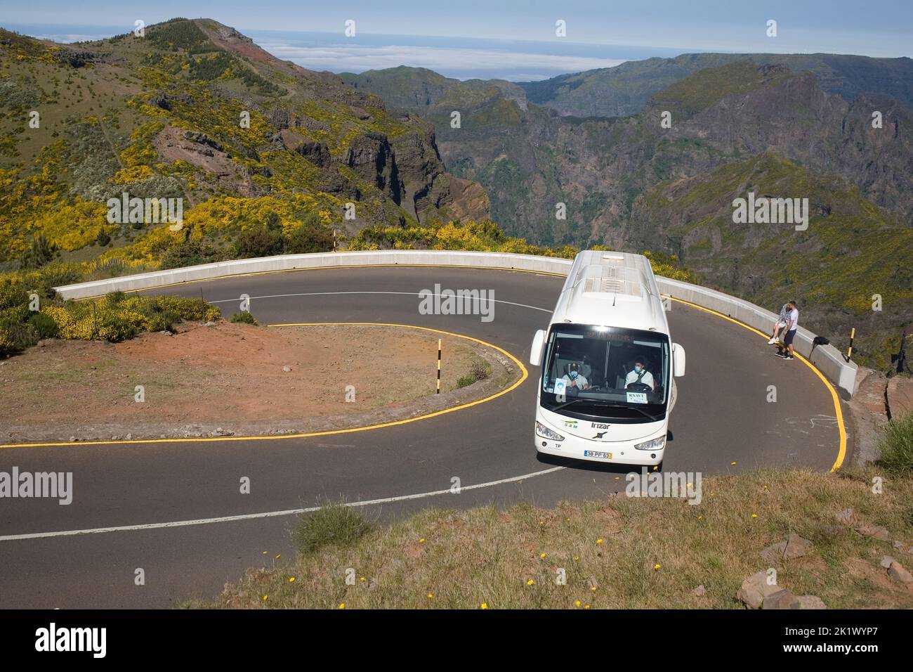 Weißer Reisebus, der eine Haarnadelkurve auf der Straße ER202 auf dem Berg Pico do Arieiro im Zentrum von Madeira fährt Stockfoto