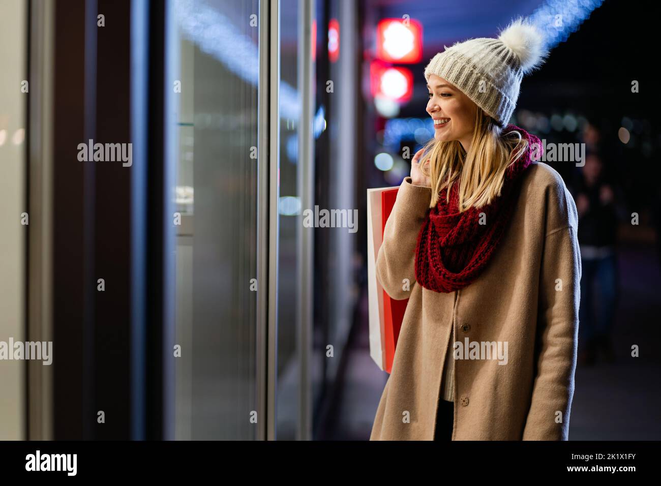 Glückliche Frau hält Einkaufstaschen und lächelt auf der Stadtstraße. Weihnachtseinkäufe, Winterverkauf Konzept. Stockfoto