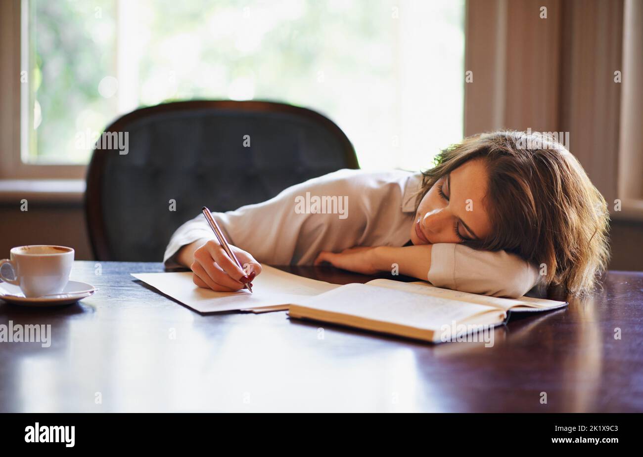 Eine attraktive junge Frau, die in einer entspannten Umgebung zu Hause schreibt. Stockfoto