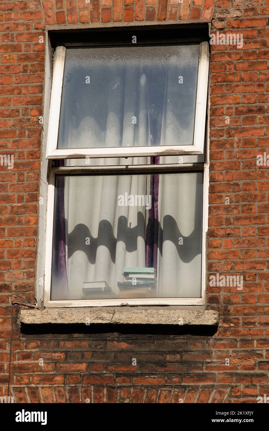 Ein teilweise geöffnetes Fenster in einem roten Ziegelgebäude. Stockfoto