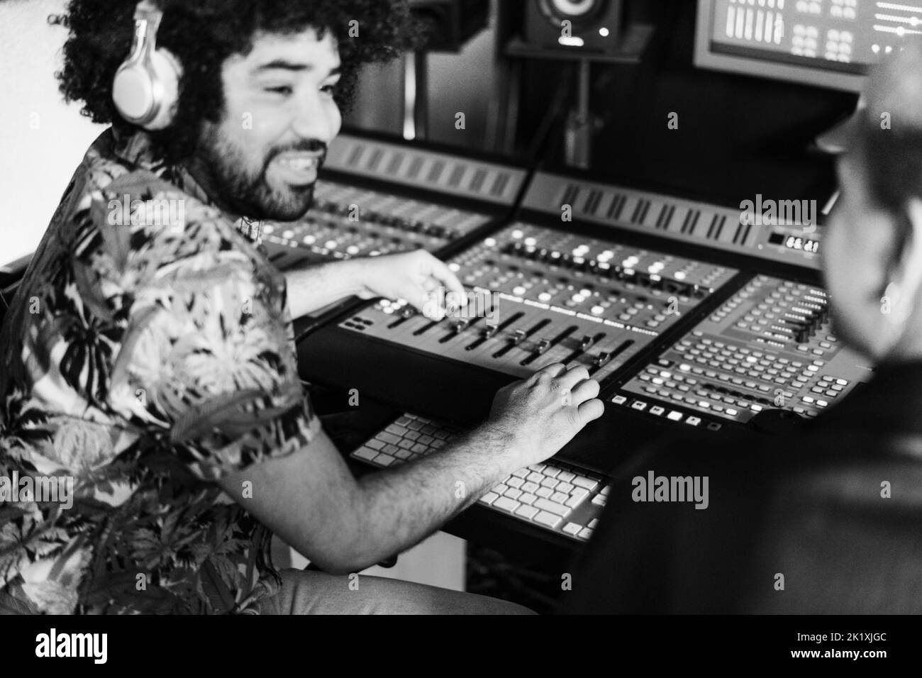 Musikproduzenten mischen neues Album im Produktionsstudio - Fokus auf Mann rechts - Schwarz-Weiß-Schnitt Stockfoto