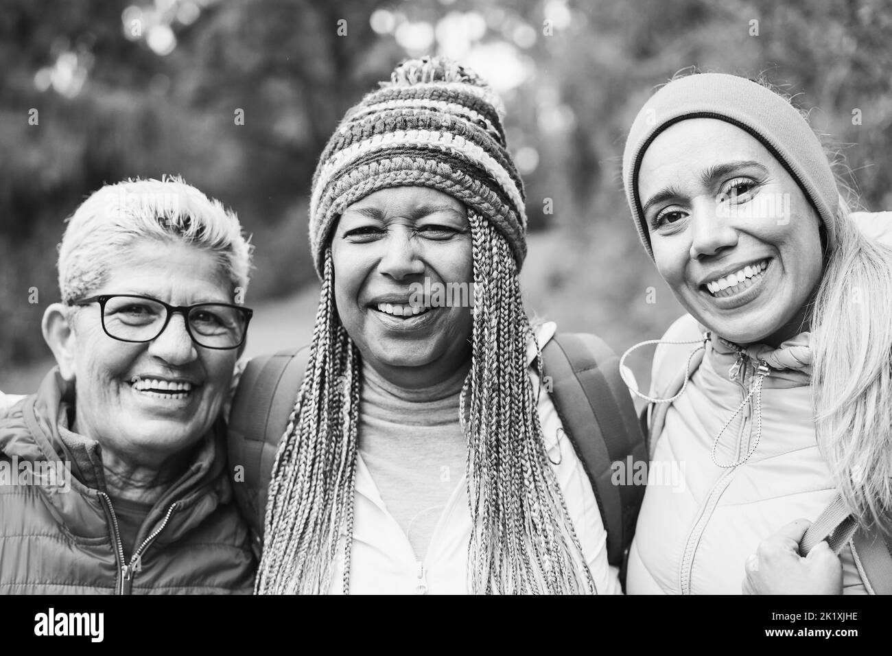 Portrait von multirassischen Freundinnen, die während des Trekkingtages im Bergwald Spaß haben - Fokus auf das rechte Frauengesicht - Schwarz-Weiß-Schnitt Stockfoto