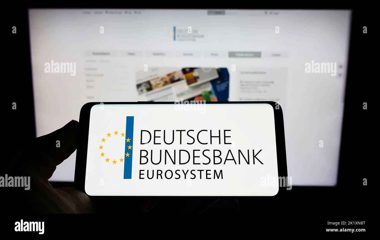 Person mit Mobiltelefon und Logo der Deutschen Bundesbank auf dem Bildschirm vor der Webseite. Konzentrieren Sie sich auf die Telefonanzeige. Stockfoto