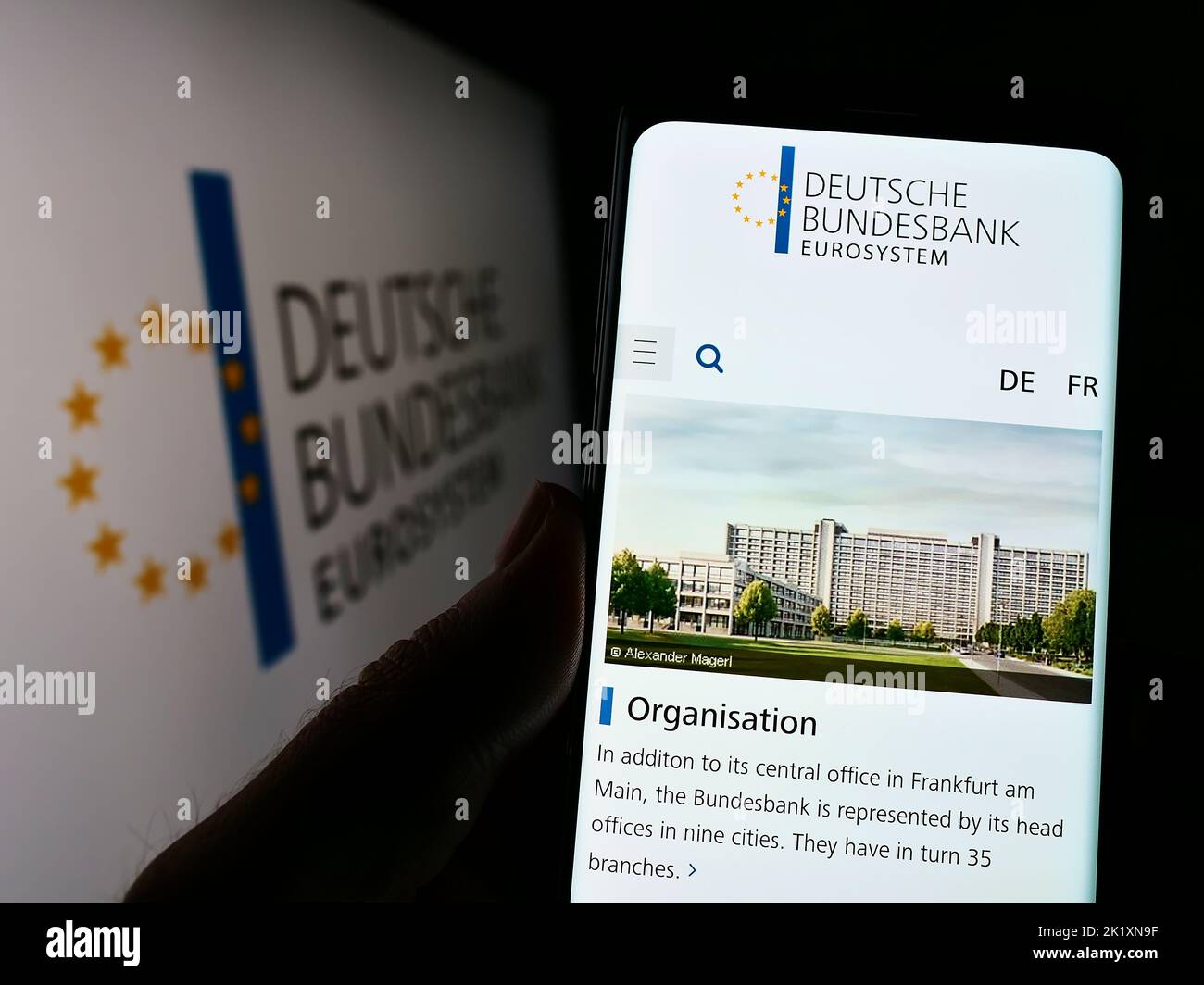 Person mit Mobiltelefon und Website der Deutschen Bundesbank auf dem Bildschirm vor dem Logo. Konzentrieren Sie sich auf die Mitte des Telefondisplays. Stockfoto