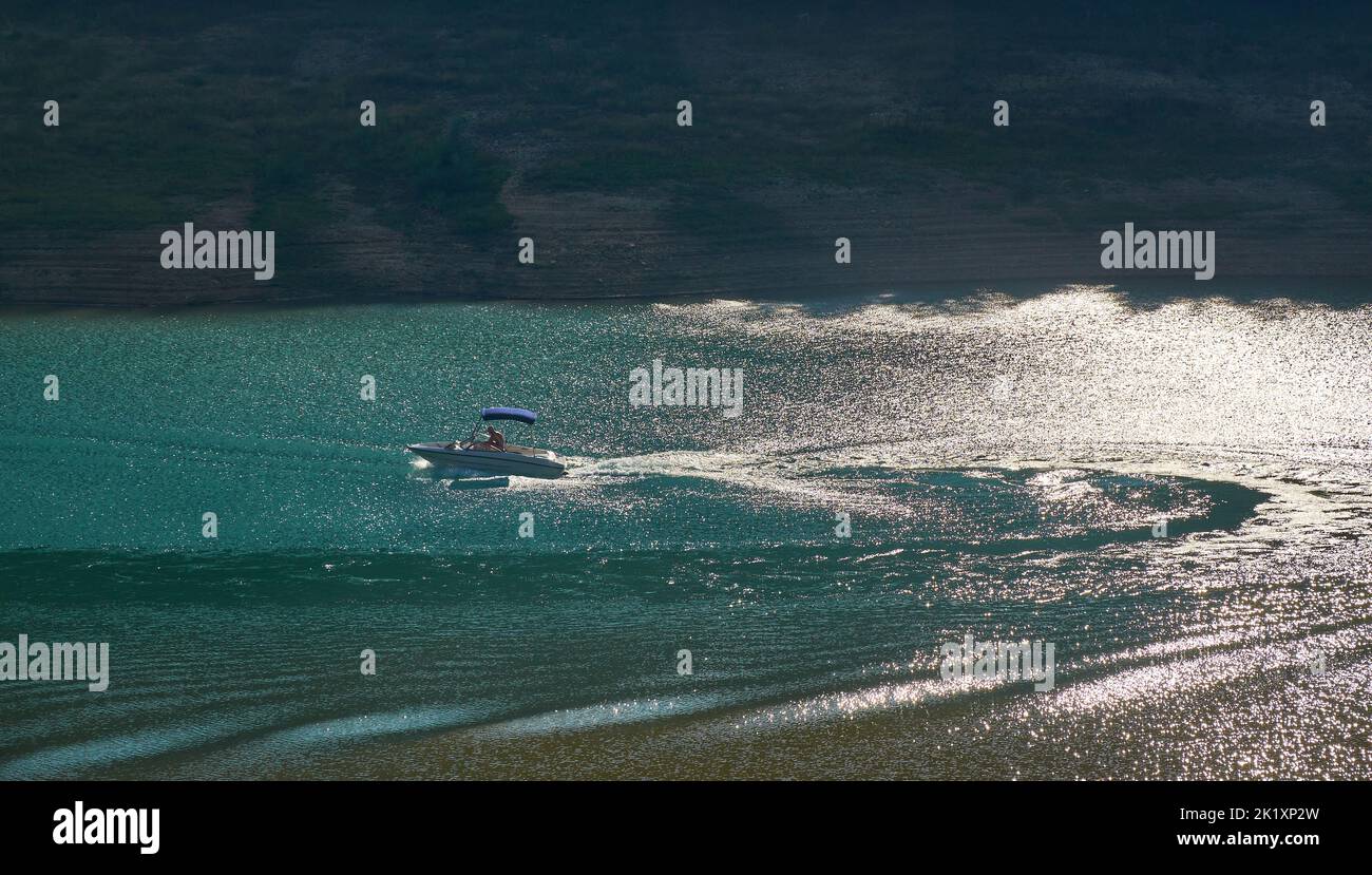 Schnellboot auf einer Fahrt, die an einem Sommertag Wellen auf einer Seenoberfläche macht Stockfoto