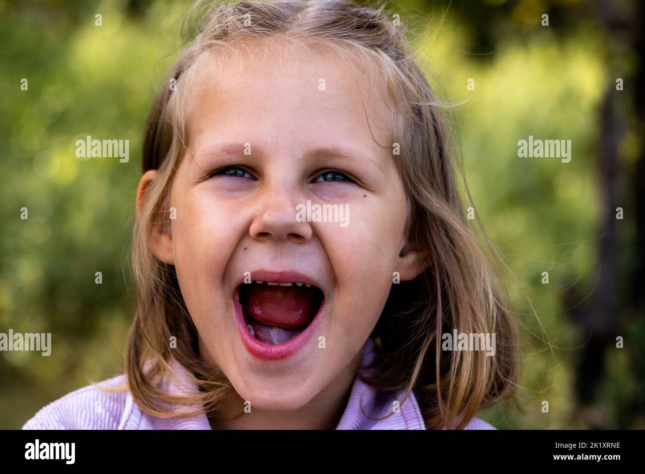 Lächelndes kleines Mädchen im Park. Speicherplatz kopieren. Glückliches Kind, das die Kamera anschaut. Porträt eines lachenden Kindes draußen. Banner. Stockfoto