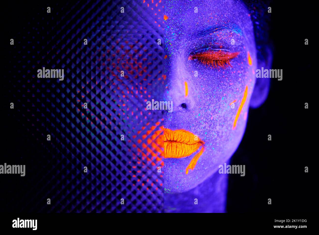Die Schönheit des Surrealen. Eine junge Frau posiert mit Neonfarbe auf ihrem Gesicht. Stockfoto
