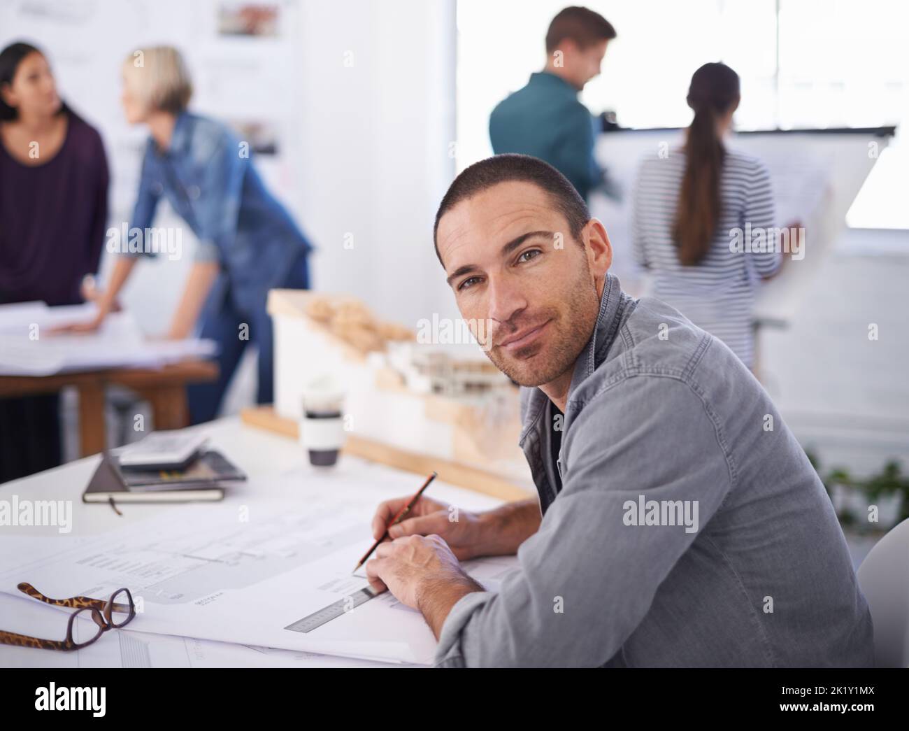 Seine Arbeit fließt gut in dieses Umfeld ein. Porträt eines hübschen Architekten, der an seinem Schreibtisch arbeitet. Stockfoto