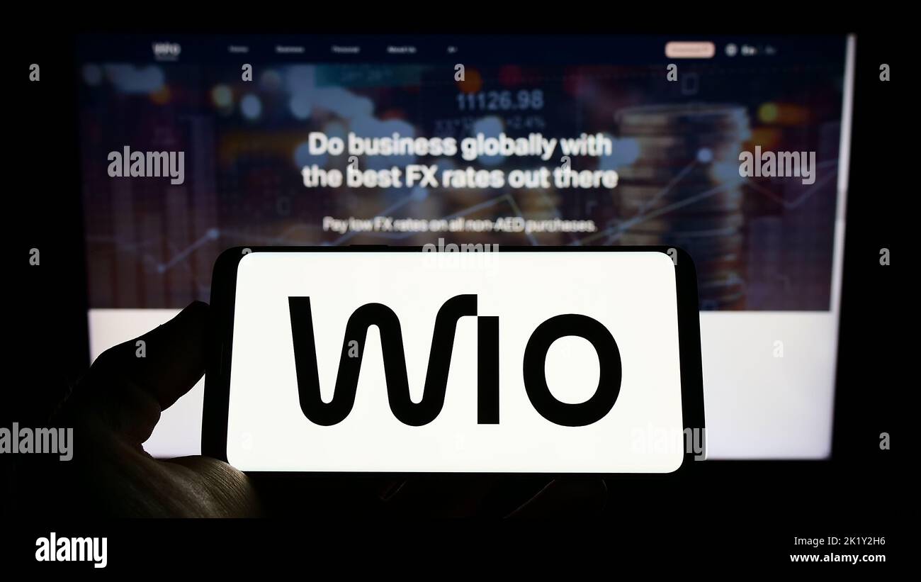Person, die ein Mobiltelefon mit dem Logo des Finanzdienstleisters Wio Bank PJSC auf dem Bildschirm vor der Unternehmenswebseite hält. Konzentrieren Sie sich auf die Telefonanzeige. Stockfoto