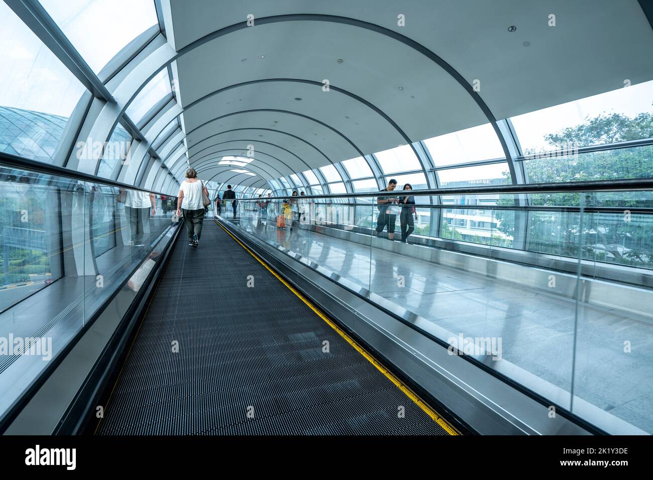 Passagiere, die mit dem Travelator zwischen den Terminals auf dem Changi International Airport in Singapur umsteigen Stockfoto