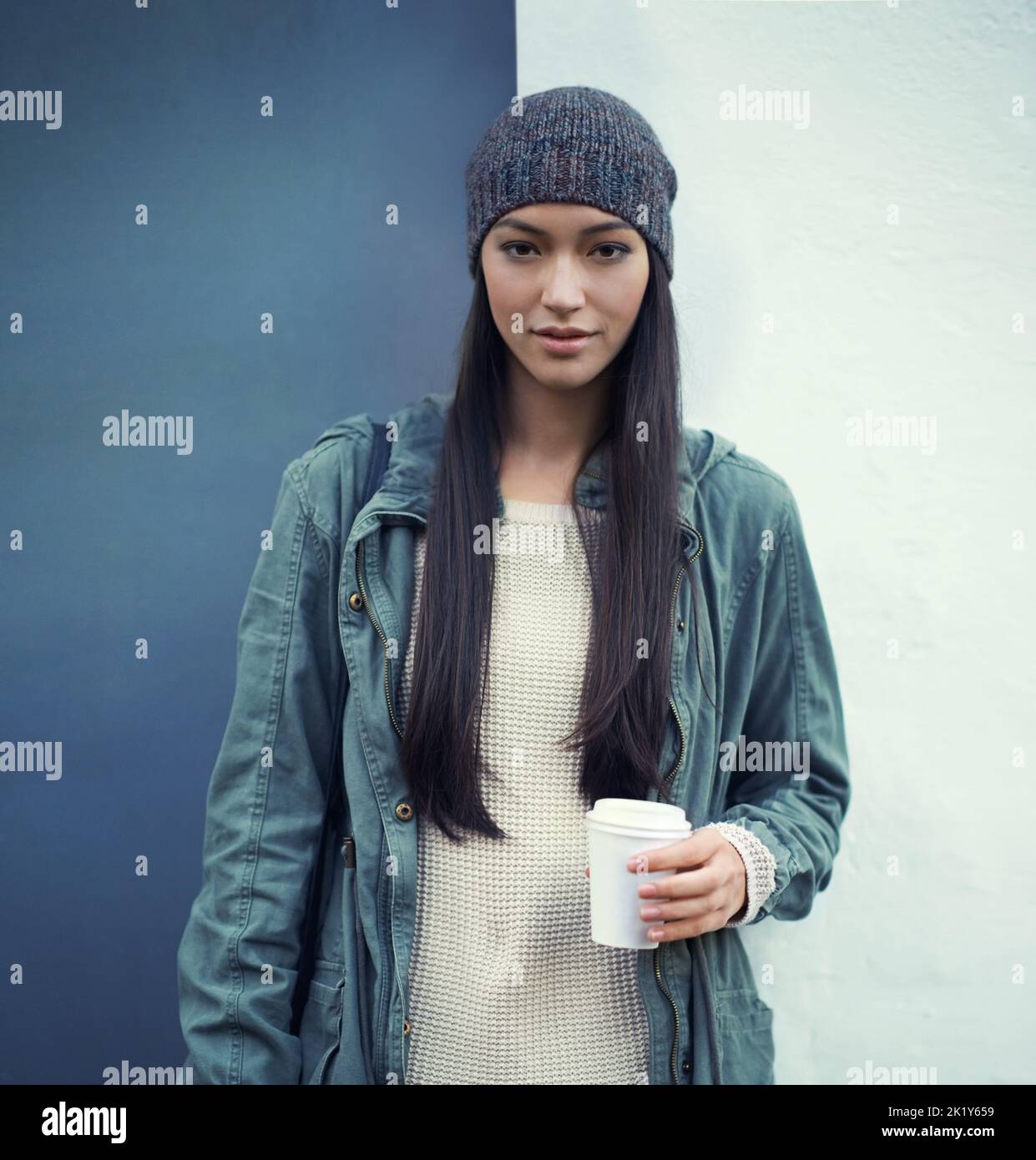 Winter in der Stadt. Porträt einer jungen Frau, die im Freien einen Kaffee zum Mitnehmen hält. Stockfoto