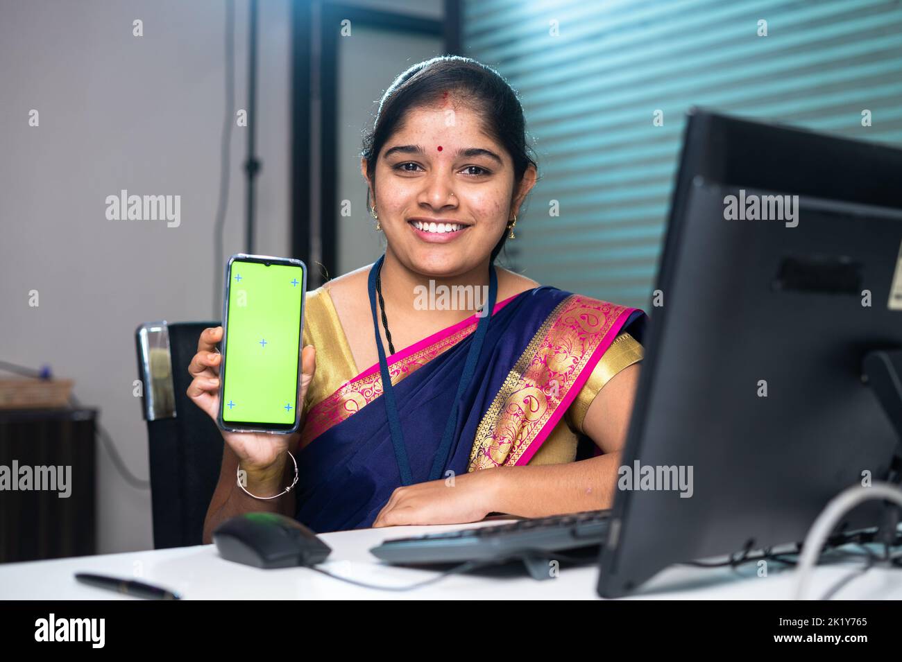 bankangestellter zeigt grünes Handy, indem er die Kamera-Bank am Schreibtisch betrachtet - Konzept der Finanzdienstleistungen, App-Werbung und Stockfoto