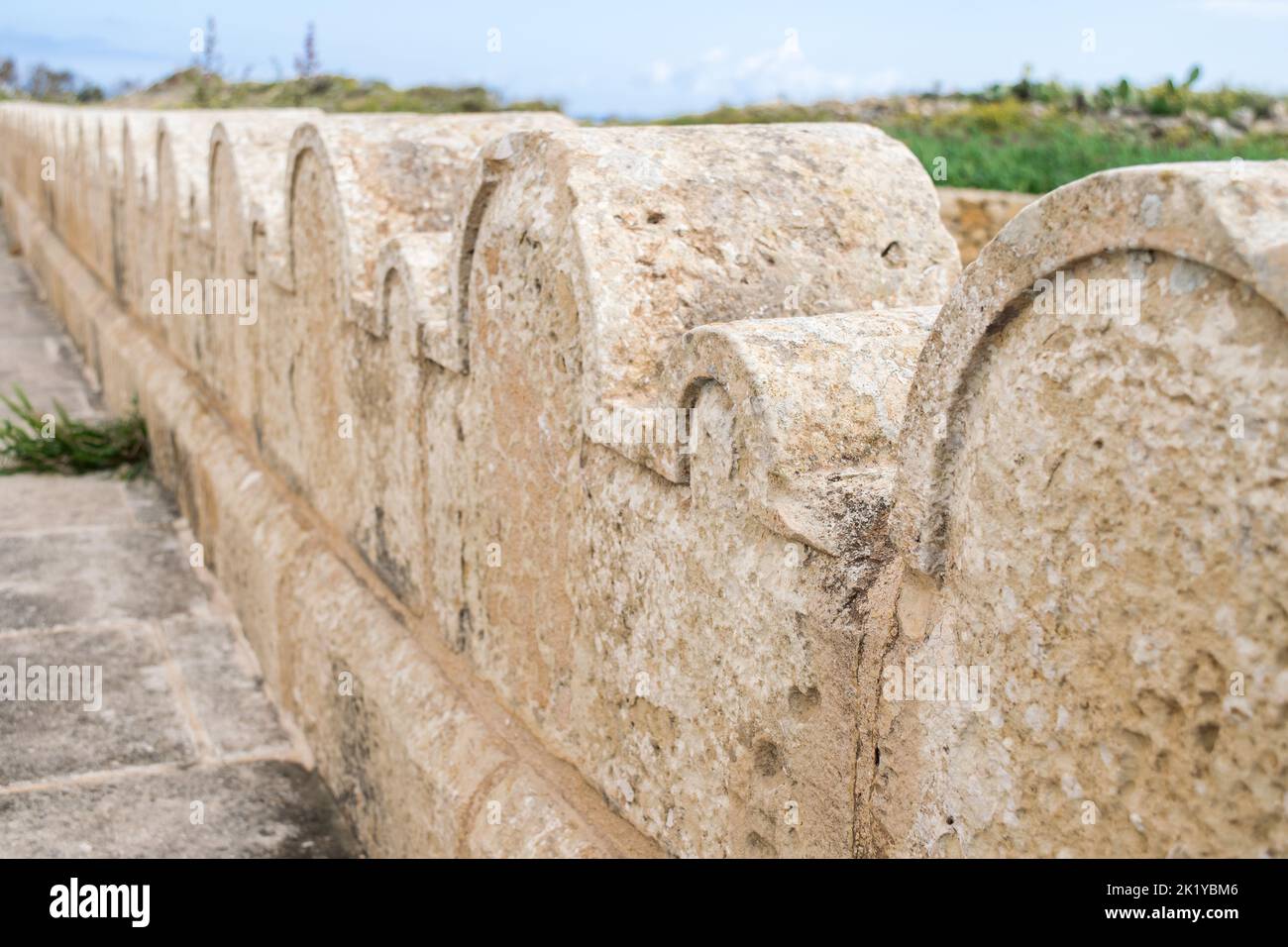 Ein Kalksteinzaun oder eine Grenze, die mit kleinen und großen Steinbögen um die St. Dimitri-Kapelle im ländlichen Dorf Gharb, Gozo, Malta, geschmückt ist Stockfoto
