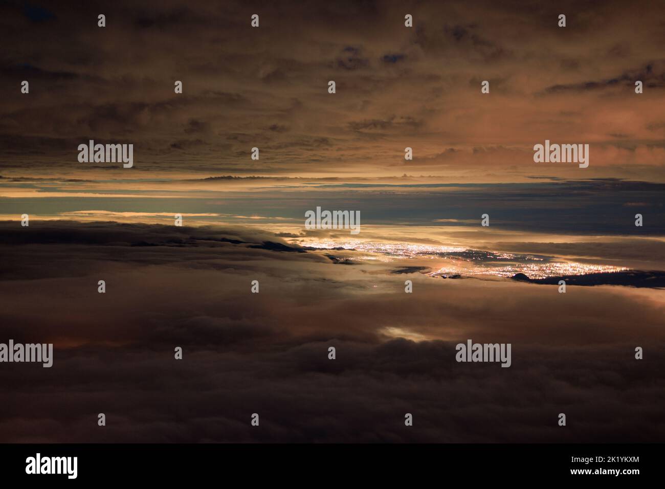 Hochgelegene Ansicht von Wolkenschichten über Lichtern aus der fernen Stadt Stockfoto