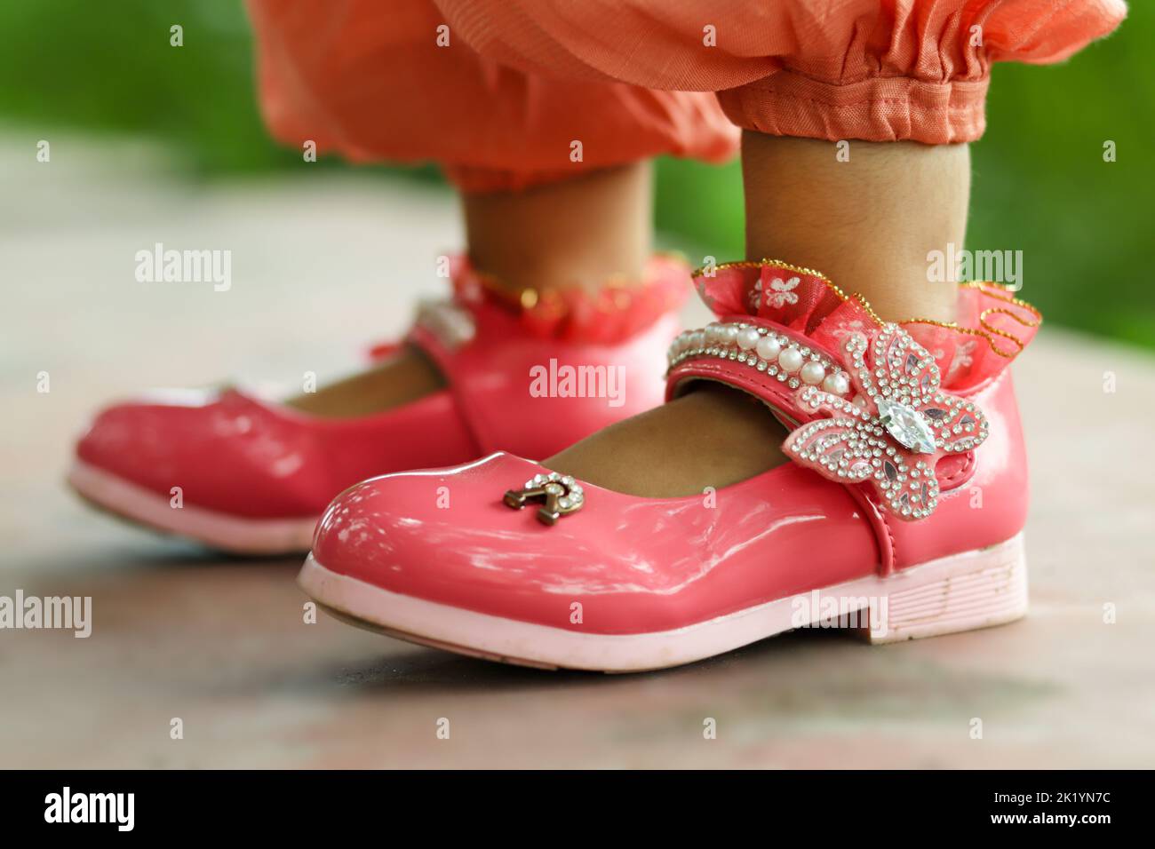 Das Mädchen trägt schöne rosa Farbe Schuhe mit der gleichen Farbe Kleid. Einige gute Optionen sind Turnschuhe, Slipper und Sandalen. Es hängt wirklich von yo ab Stockfoto