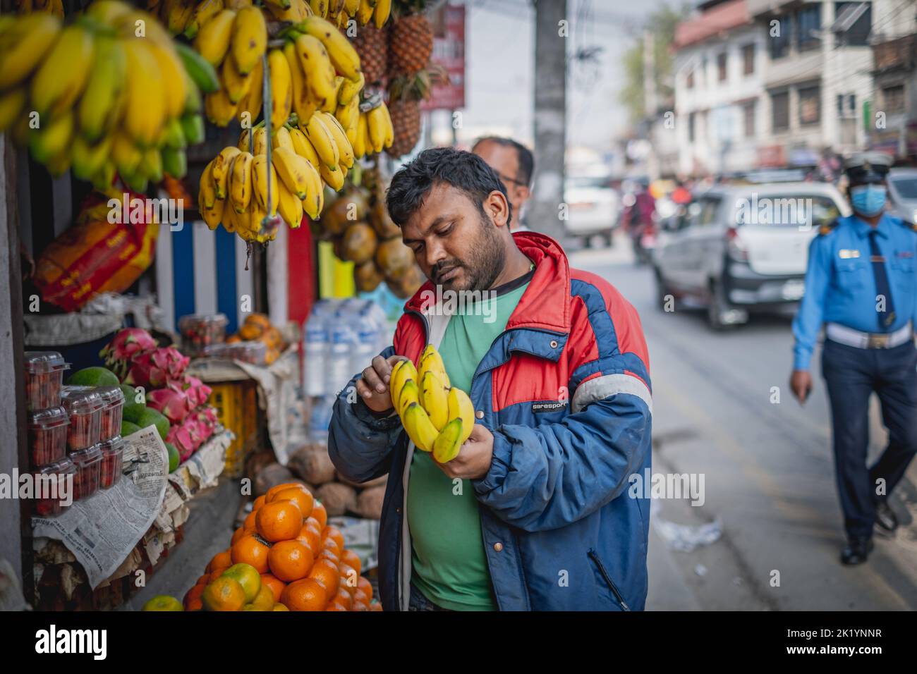 Ein Mann, der Bananen in einem lokalen Geschäft in Kathmandu, Nepal, untersucht Stockfoto
