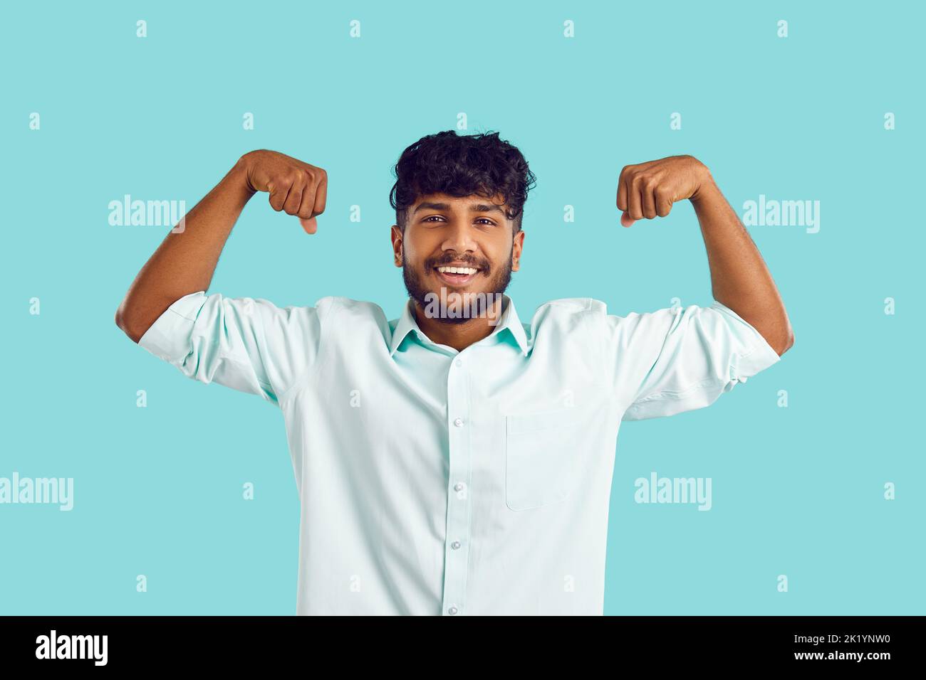 Lächelnder indischer Mann zeigt Muskeln zeigen Kraft Stockfoto