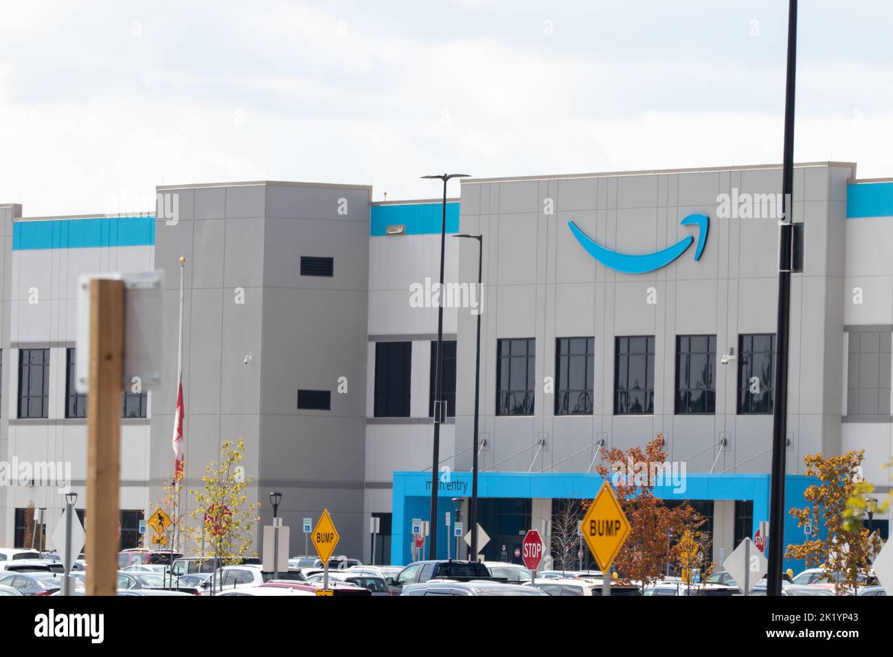 Der Eingang zu einer Amazon-Versandeinrichtung während des Tages; das berühmte blaue Amazon-Logo befindet sich an der Vorderseite des Gebäudes. Stockfoto
