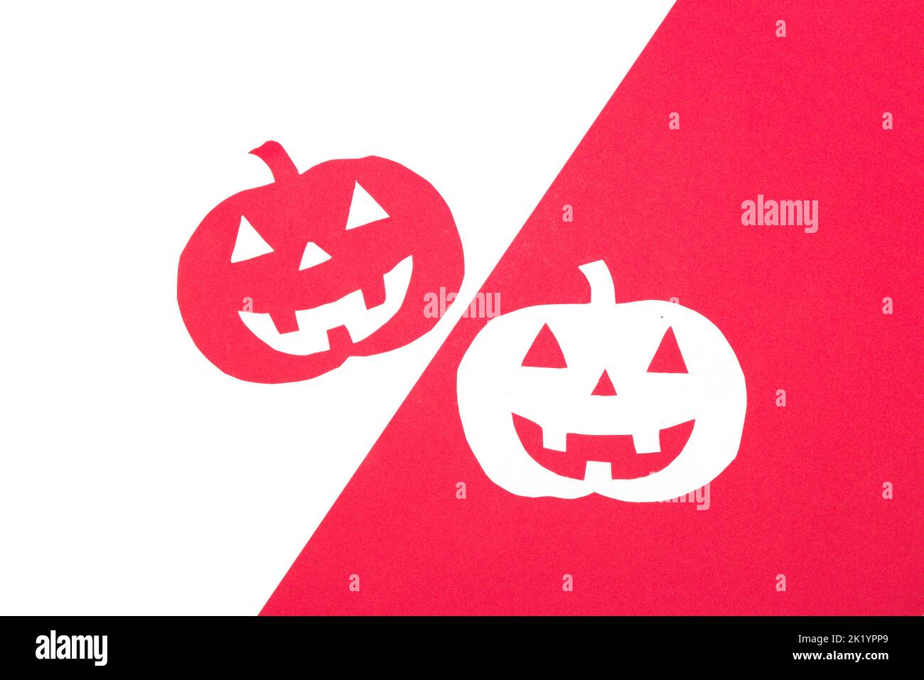 Roter Kürbis auf einem weißen Teil des Hintergrunds, weißer Kürbis auf einem roten Teil des Hintergrunds, kreatives halloween-Design, flaches Lay Stockfoto