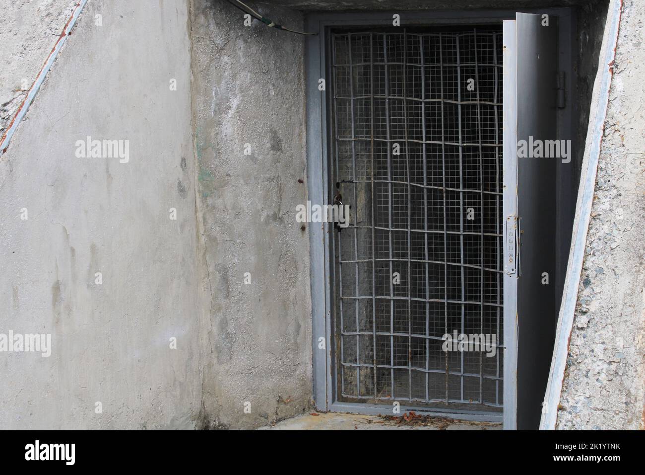 Offene Tür zum Keller mit Bars in einem alten Steingebäude. Stockfoto