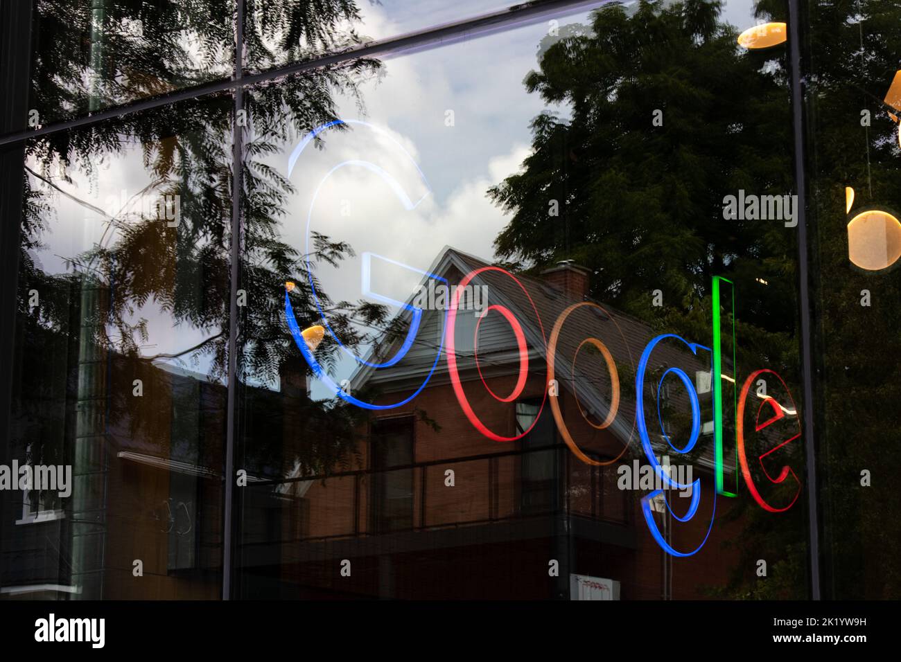 Ein farbenfrohes, beleuchtetes Google-Logo in einem Bürogebäude in Kitchener, Kanada; an einem sonnigen Tag durch ein Fenster zu sehen. Stockfoto